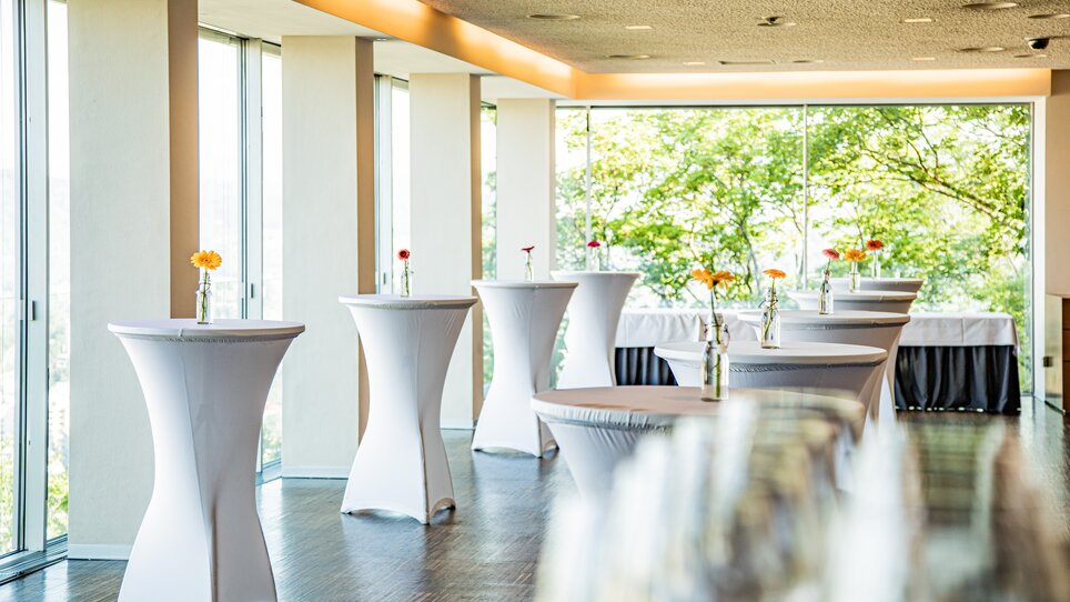 Space in Restaurant SCHLOSSBERG featuring elegant standing tables and large windows, perfect for business events. | © Restaurant SCHLOSSBERG - Werner Krug