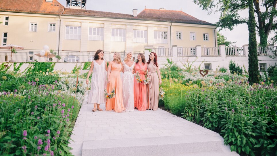 Group photo of bridesmaids in pastel dresses in the garden. | © Pixellicious Fotografie