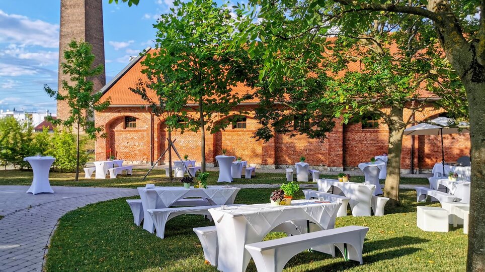 Im Außenbereich der Seifenfabrik Graz sind stilvolle Tische und Bänke für Events aufgestellt. Ideal für Konferenzen und Networking. | © Seifenfabrik Veranstaltungszentrum
