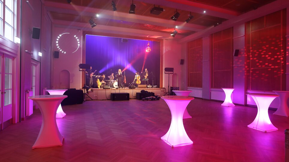 An event space with a live band, illuminated by pink lights. | © Universalmuseum Joanneum - JJ. Kucek