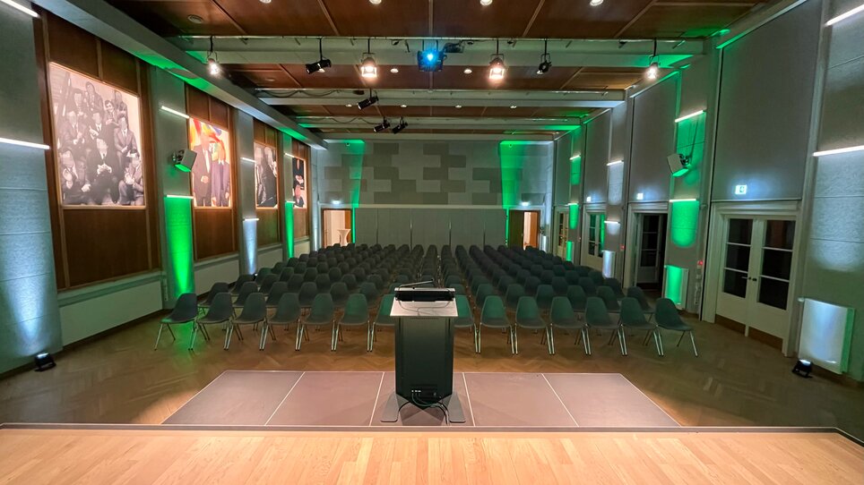 Conference room with rows of chairs and green lighting, ready for an event. | © UMJ - N. Noriller