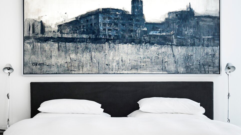 Eine stilvolle Inneneinrichtung im Penthouse des Augarten Art Hotels mit modernem Gemälde und eleganter Bettwäsche. | © Augarten Art Hotel