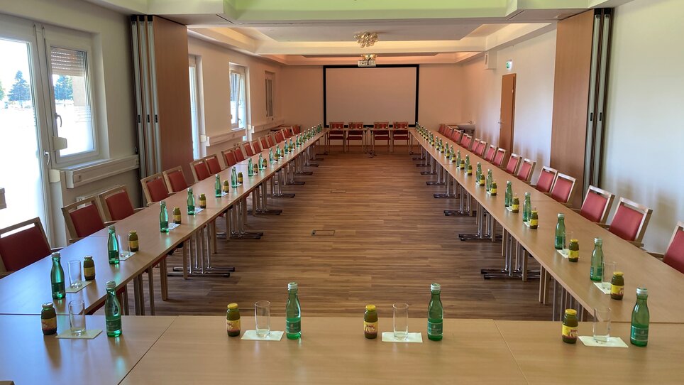 Setup of a conference room with tables, chairs, and water bottles at Hotel Der Stockinger. | © Der Stockinger