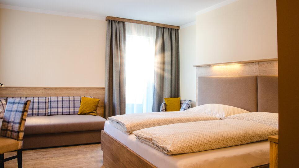 Modernes Zimmer mit Doppelbett und Sitzecke im Hotel-Gasthof Pendl. | © Mias Photoart