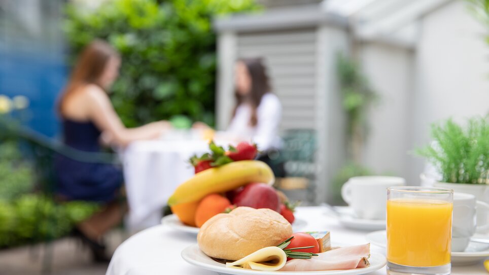 A table set outdoors for breakfast with bread, cold cuts, fruits, and juice at Hotel Gollner. | © Hotel Gollner