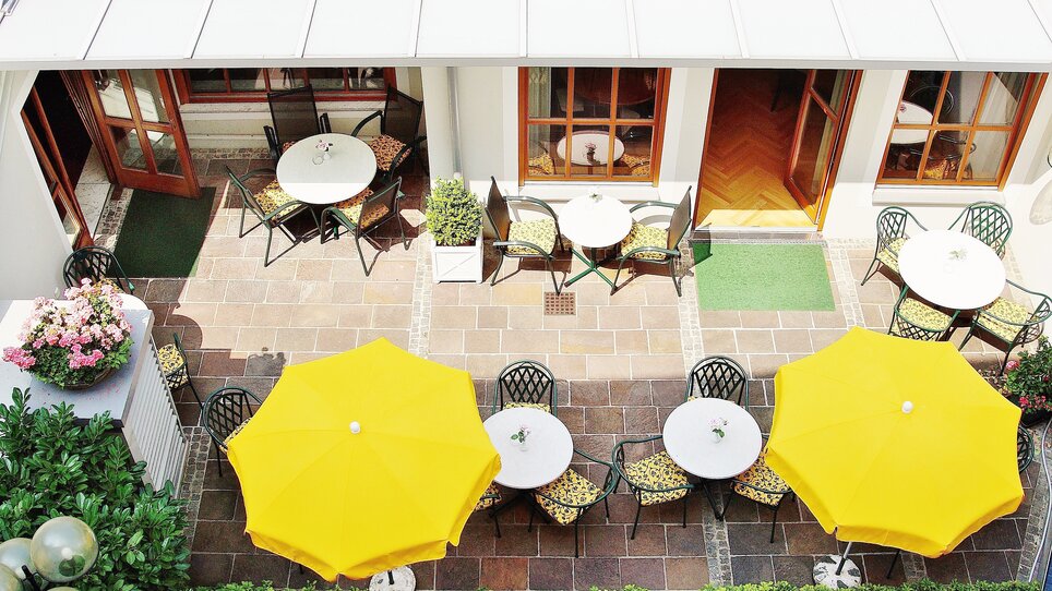 A terrace with tables, chairs, and yellow umbrellas at Hotel Gollner. | © Hotel Gollner