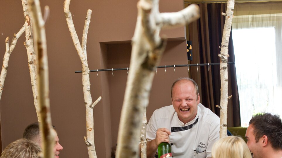 Ein Küchenchef serviert Speisen an Gäste im Restaurant des Hügellandhofs. | © Hügellandhof