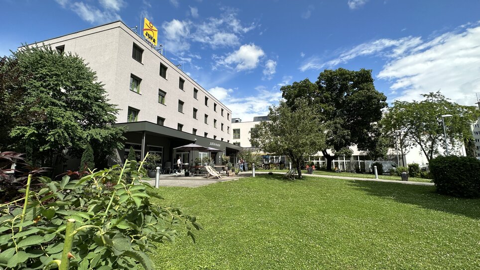 Außenansicht des JUFA Hotels Graz City mit Sitzgelegenheiten im Garten für Tagungen und Geschäftsreisen. | © JUFA Graz City