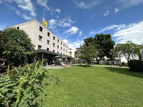 Außenansicht des JUFA Hotels Graz City mit Sitzgelegenheiten im Garten für Tagungen und Geschäftsreisen. | © JUFA Graz City