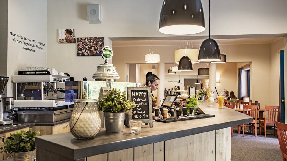 Café-Bereich mit einer Theke, einem Barista und Cocktails im JUFA Hotel Maria Lankowitz. | © LenzJUFA Hotels