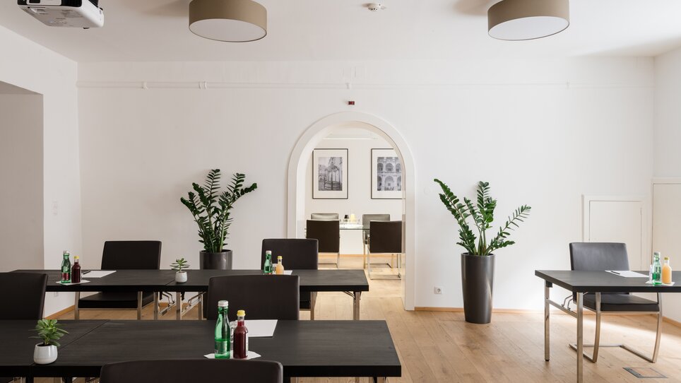Heller Meetingraum im Hotel Mariahilf mit Tischen, Pflanzen, Getränken und Projektor. | © Hotel Mariahilf