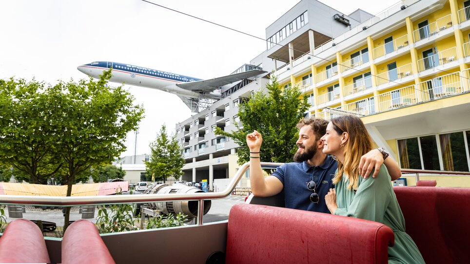 Paar im Novapark Flugzeughotel mit einem Flugzeug im Hintergrund. | © Graz Tourismus - Werner Krug