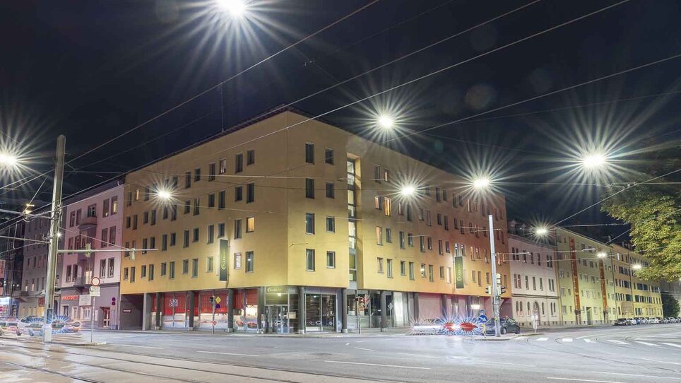Beleuchteter Stadtbereich in Graz bei Nacht mit dem Hotel PLAZA INN Graz City und Straßenlaternen. | © PLAZA INN Graz City - Martin Thalmann