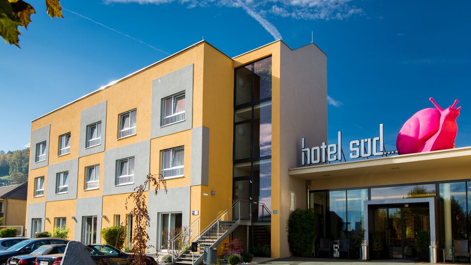 Außenansicht des Hotel Süd mit pinkfarbener Schnecke und Unterstützung für Businessreisen. | © Hotel Süd Art