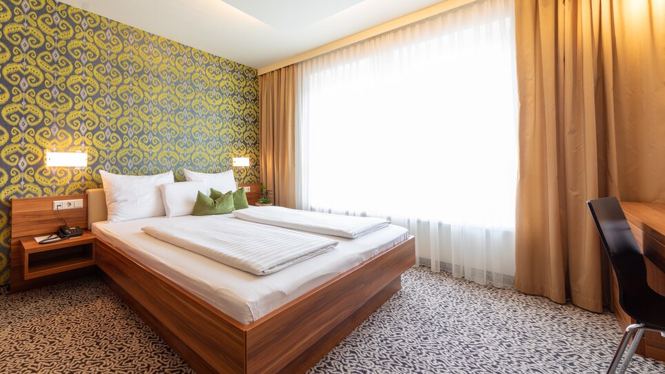 Zimmer im Hotel Süd mit Doppelbett und Blick auf den Balkon. | © Hotel Süd Art