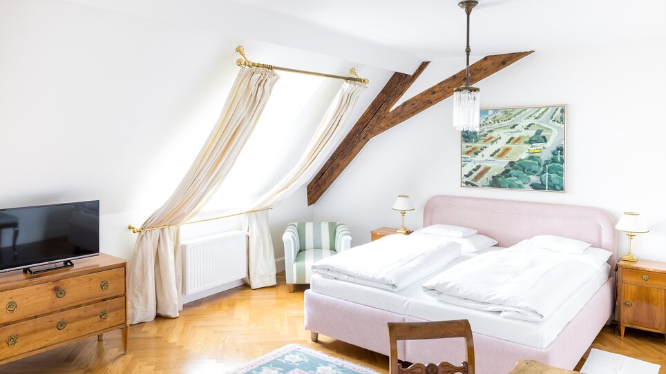Bright bedroom with double bed, TV, and window view at the Schlossberghotel. | © Schlossberghotel