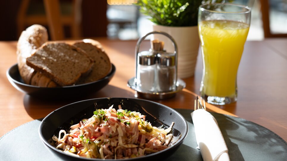 A plate with salad, bread, and a drink on a table. | © Hotel Stoiser Graz