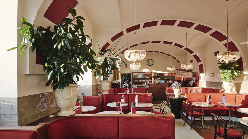 Blick ins Kaffeehaus des Hotel Weitzer mit roten Sitzgelegenheiten und Pflanzen. | © Florian Weitzer Hotels & Restaurants