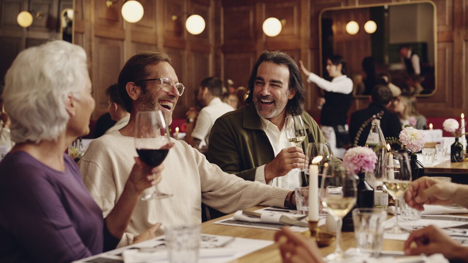 Freunde genießen ein Abendessen im Restaurant Der Steirer des Hotel Weitzer und stoßen mit Weingläsern an. | © Florian Weitzer Hotels & Restaurants