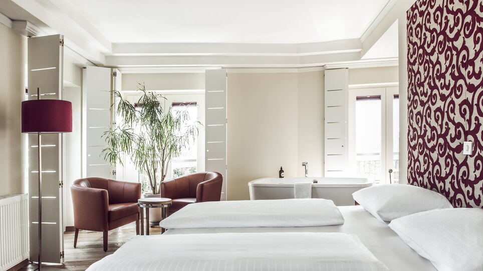 Innenansicht eines Hotelzimmers im Hotel Das Weitzer in Graz, mit zwei Betten, Stühlen und einer Pflanze. | © Florian Weitzer Hotels & Restaurants