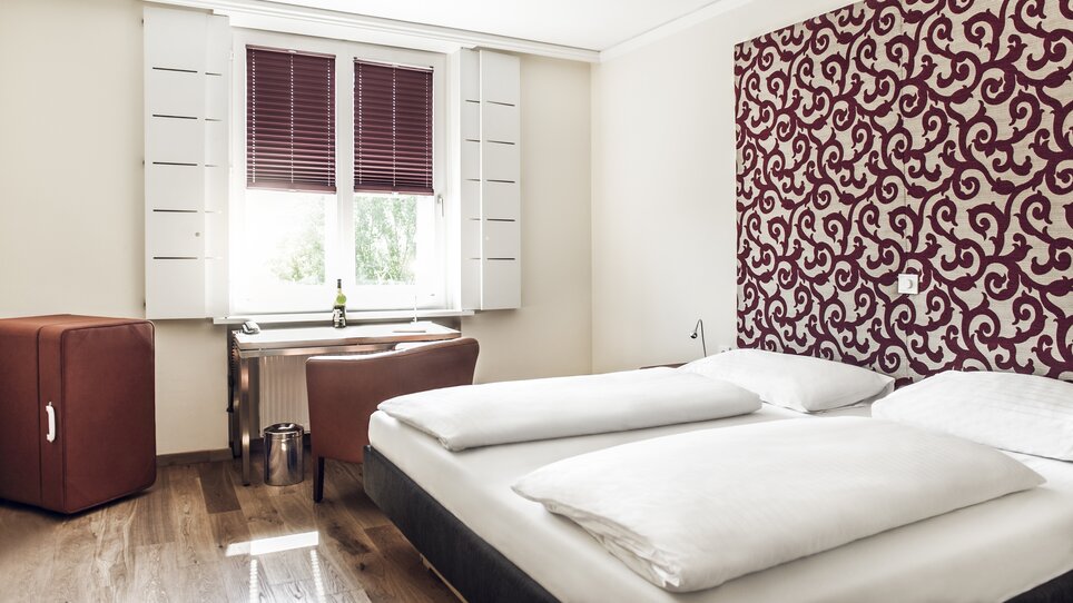 Einblick in ein Zimmer im Hotel Weitzer in Graz mit Doppelbett und Arbeitsplatz. | © Florian Weitzer Hotels & Restaurants