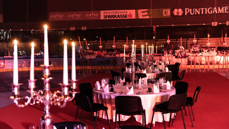 Ein festlich gedeckter Saal mit runden Tischen und Kerzenleuchtern in einer Veranstaltungshalle. Die Location bietet hochwertige Möbel und Beleuchtung. | © AMB GmbH