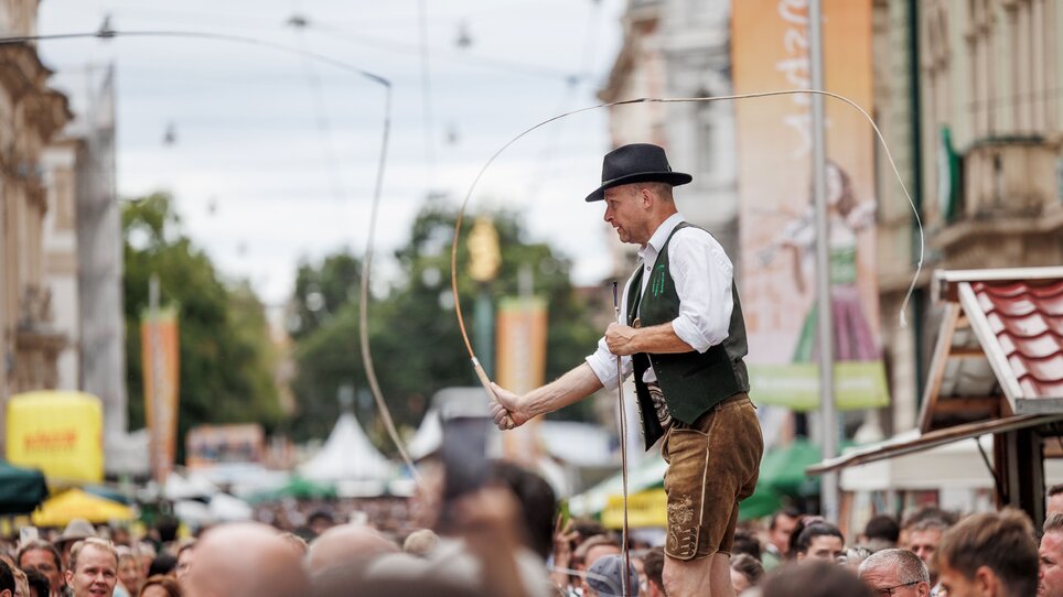 Ein Schnalzer unterhält die Menge auf einem traditionellen Fest. | © Erwin Scheriau