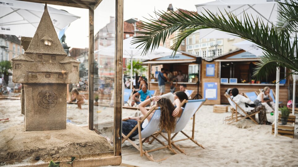 Blick auf eine Sandburg und entspannte Menschen am Strand beim Summer Feeling in the City Festival in Graz. | © Ulrike Rauch