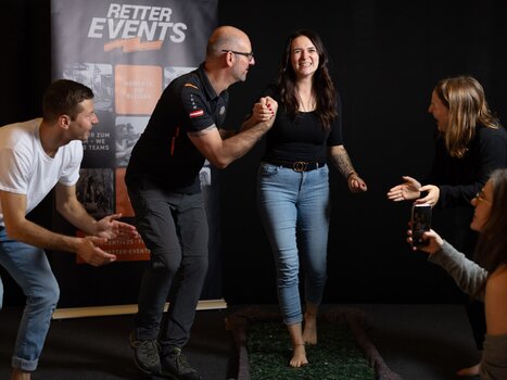 Individuals engaged in an interactive team exercise with laughter and support. | © Retter Events