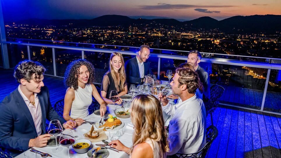 Eine Gruppe von Menschen genießt ein stilvolles Dinner mit Aussicht auf Graz. | © Graz Tourismus - Mias Photoart