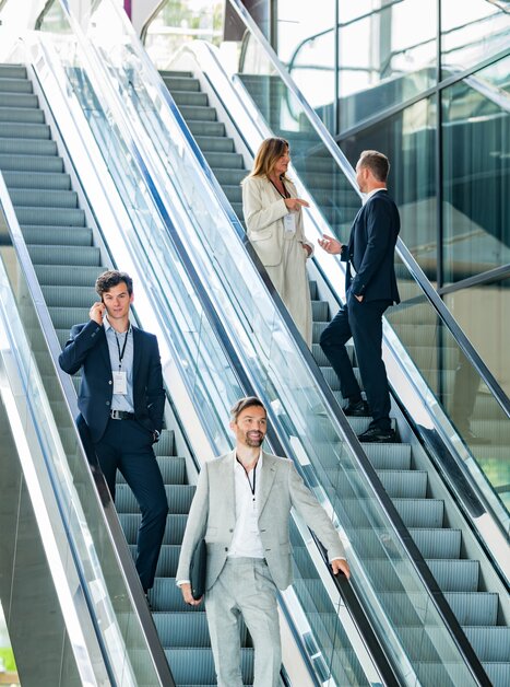 Business professionals in formal attire interact in modern architecture. | © Graz Tourismus - Mias Photoart