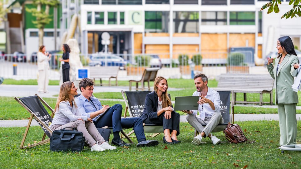Vier Personen bei einer Besprechung im Freien in Graz, Zusammenarbeit hervorgehoben. | © Graz Tourismus - Mias Photoart