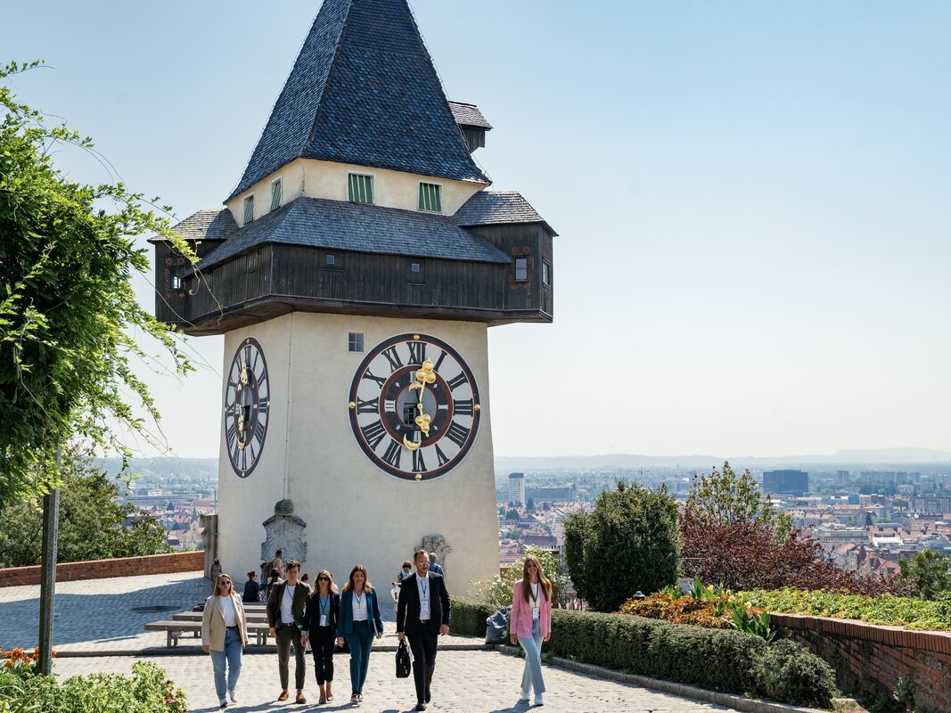 A group of people walking in front of the Graz Clock Tower. | © Graz Tourismus - Mias Photoart