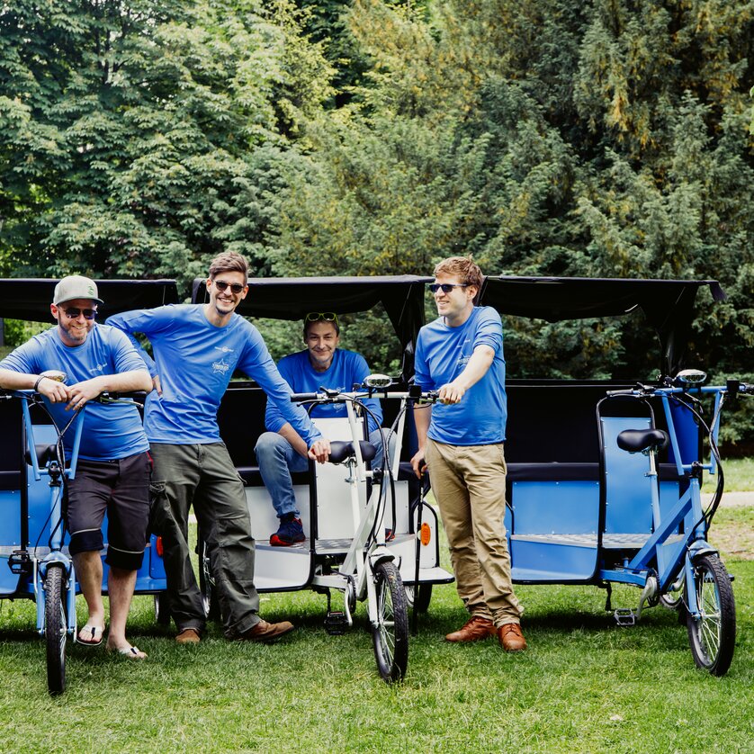 Four men stand next to bicycle rickshaws in a park in Graz. | © Claudia Plattner