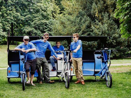 Four men stand next to bicycle rickshaws in a park in Graz. | © Claudia Plattner