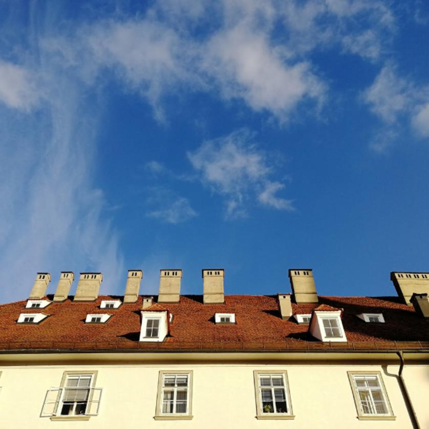 Foto Haus mit heller Fassade und vielen Schornsteinen vor blauem Himmel | © Ruth Nezmahen