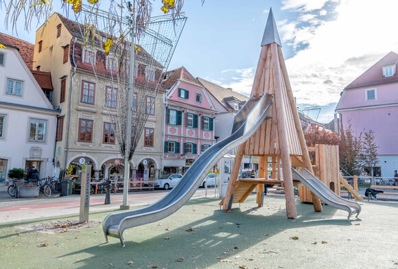 Ein moderner Spielplatz in Graz mit zwei silbernen Rutschen.