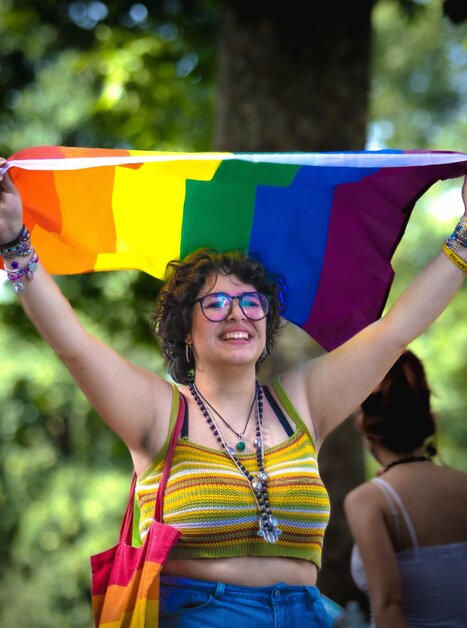 A joyful young woman raises a rainbow flag. | © pixabay
