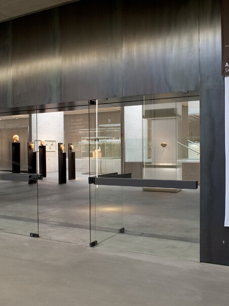 Modern glass entrance to the Archaeological Museum with exhibits. | © UMJ - N. Lackner