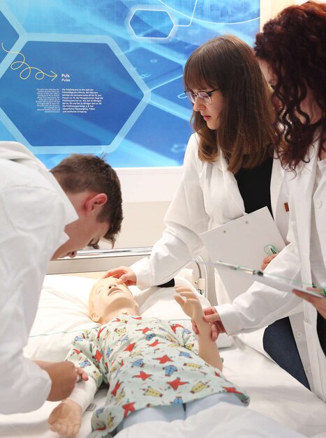 Three individuals practice on a medical training mannequin in a training facility. | © Universalmuseum Joanneum - J. Kucek