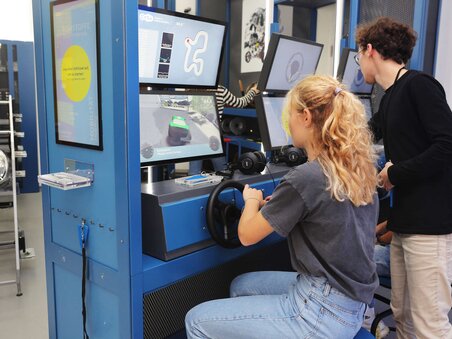 Two young people testing a vehicle racing simulator in a modern setting. | © Universalmuseum Joanneum - J. Kucek