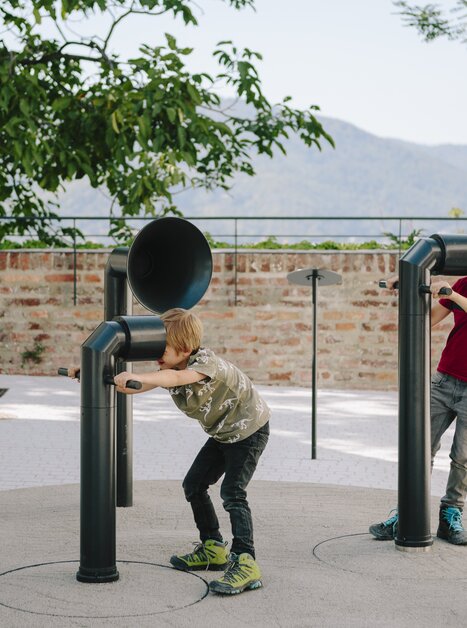 Zwei Jungen spielen an Klangskulpturen im Freien, begeistert von den Geräuschen. | © Sebastian Reiser