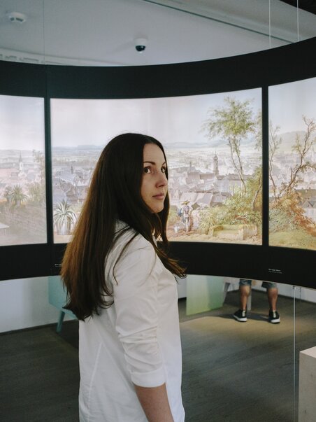 Eine Person steht vor Gemälden im Graz Museum Schlossberg. | © Sebastian Reiser