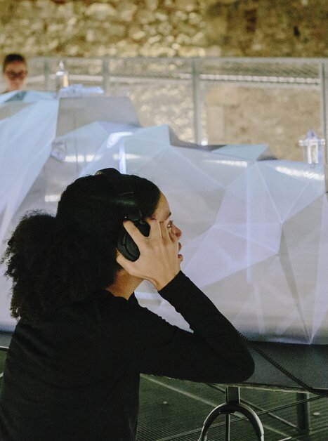 Besucherin mit Kopfhörern in einer Ausstellung mit einem 3D-Objekt. | © Sebastian Reiser