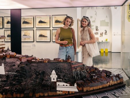 Two women look at a detailed city model of Graz in the museum. | © Graz Tourismus - Mias Photoart