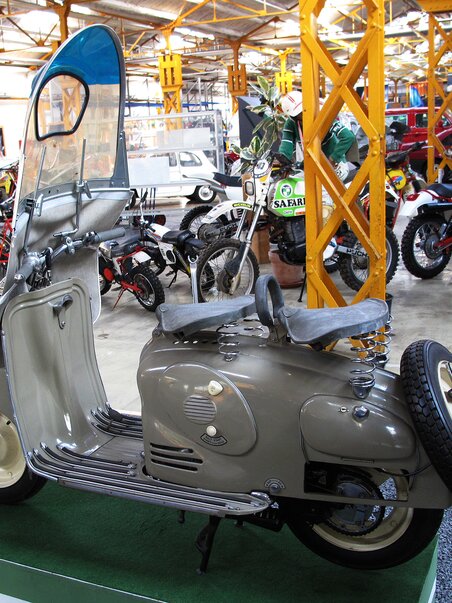 A retro motorcycle sculpture in a museum surrounded by other vehicles. | © Johann Puch Museum