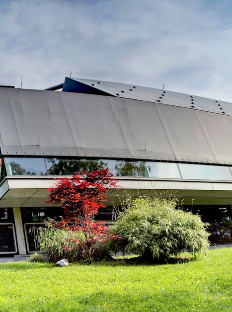 Das Bild zeigt einen modernen Bau in Graz, umgeben von grüner Wiese und Bäumen. | © Hannes Loske