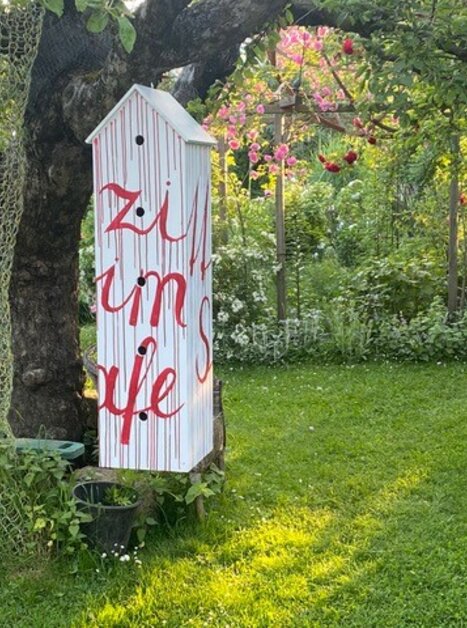 A colorful sign in the garden with the text 'zi um je'. | © kunstGarten
