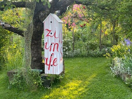 Ein farbenfrohes Schild im Garten mit dem Text 'zi um je'. | © kunstGarten