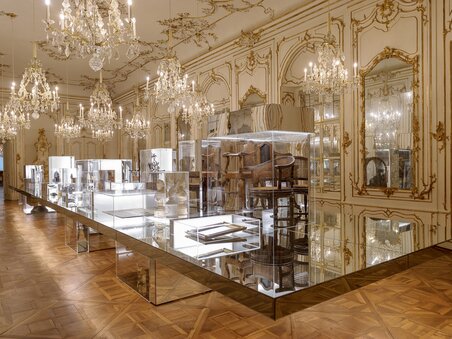 A lavish exhibition hall with display cases and chandeliers. | © UMJ - N. Lackner